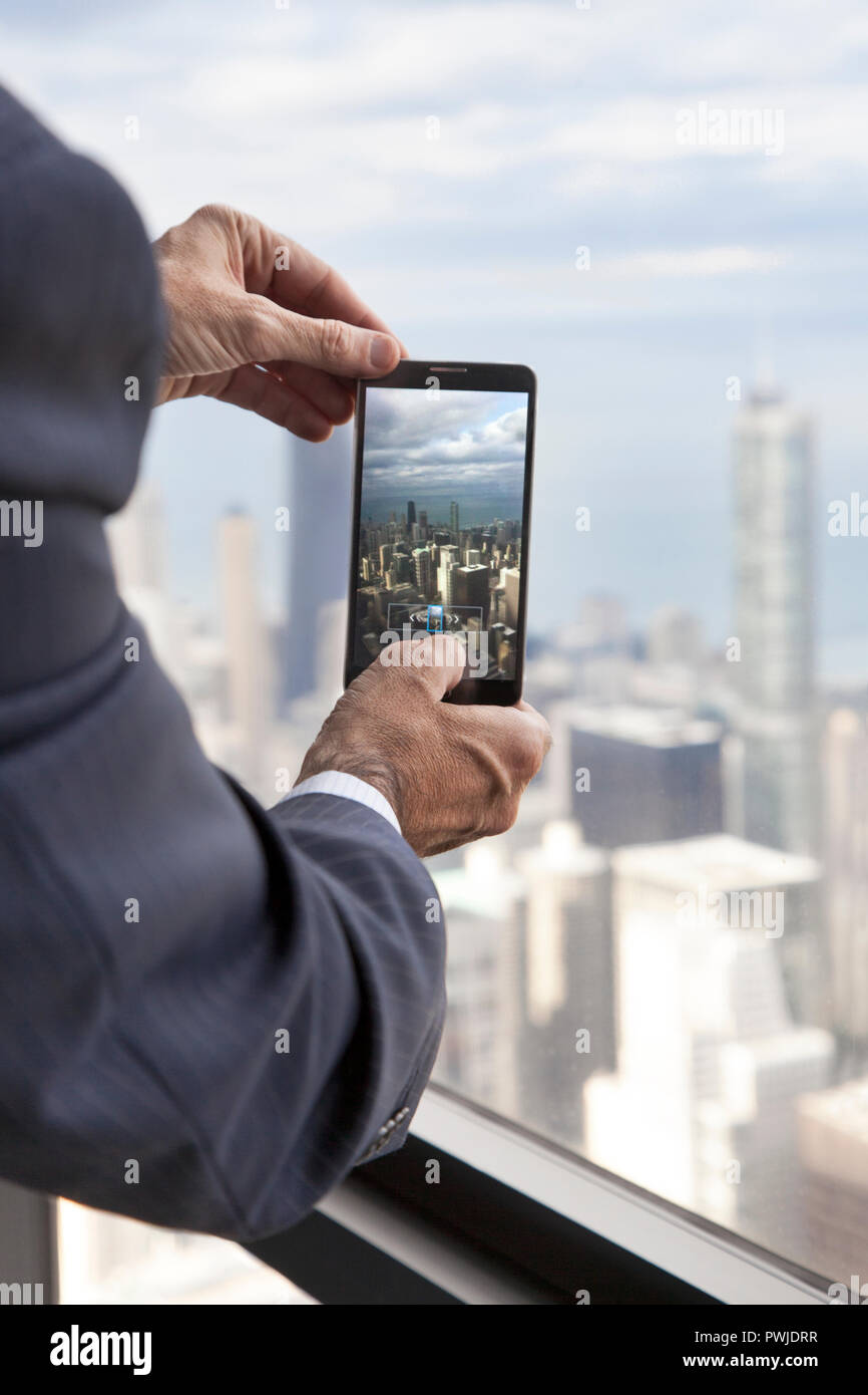 Businessman at Willis Tower taking a picture of Chicago skyline with his phone Stock Photo