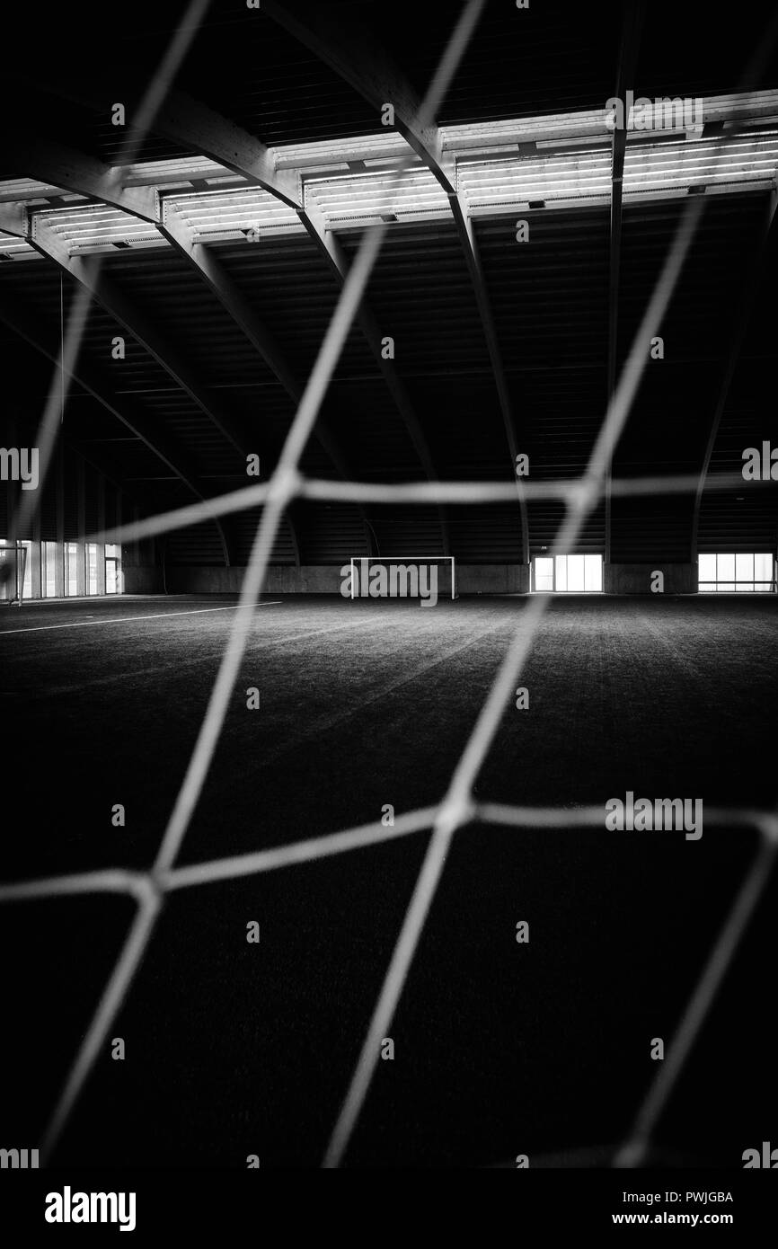 An empty indoor football / soccer artificial grass training pitch with goals and netting in Iceland for all year use. B/W Stock Photo