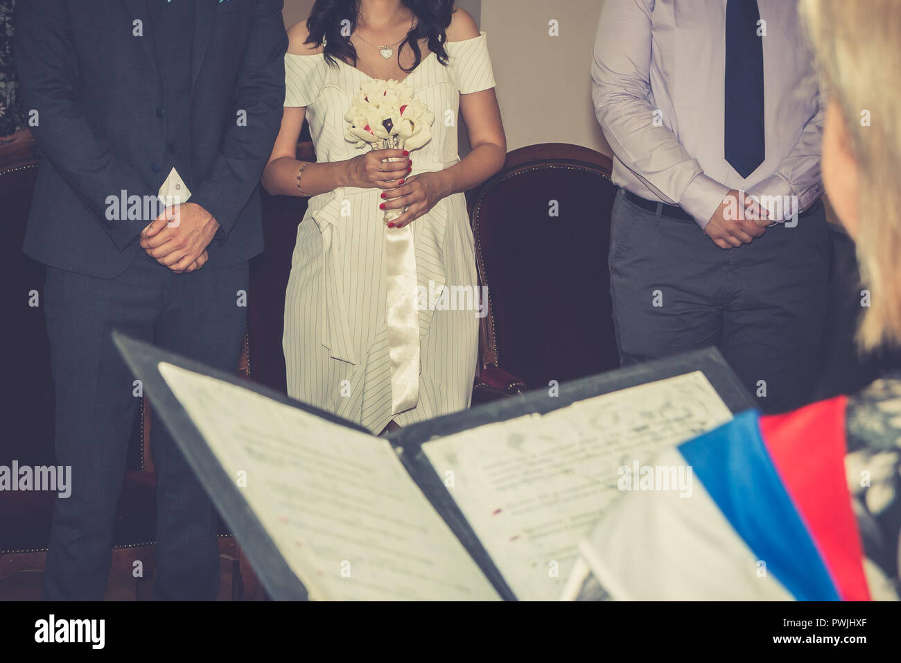 Marriage registrar reading marriage contract in civil registry office. Selective focus on bride
