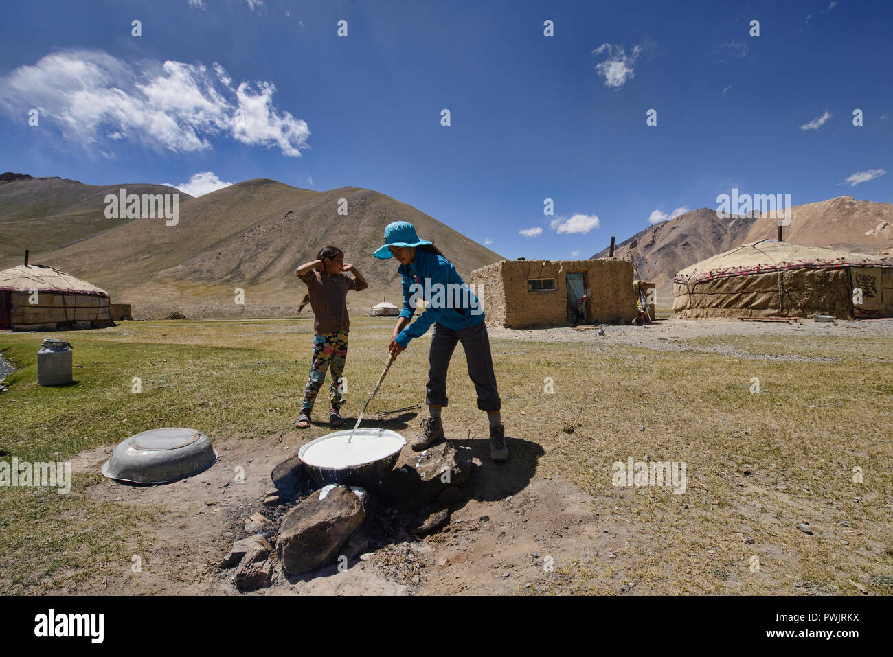 Tourist help Kyrgyz nomad making dairy products, Pshart Valley, Tajikistan Stock Photo