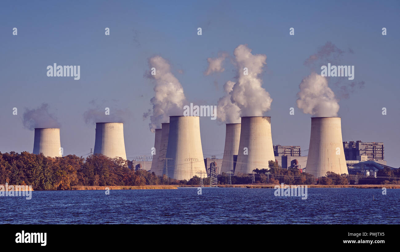 Smoking chimneys next to a lake, environmental pollution concept, color toning applied. Stock Photo