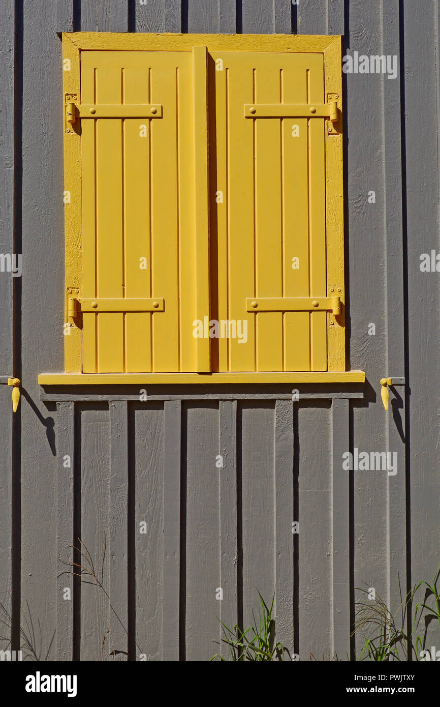 Traditional yellow shutters captured on an oyster fishermans home in Le Canon, South West France. Stock Photo