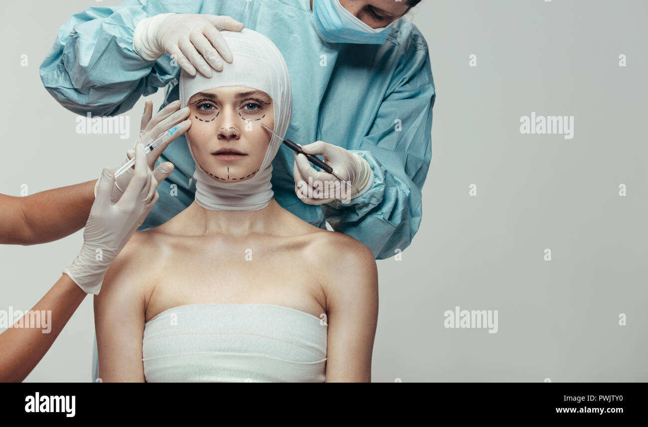 Young woman under going face lift surgery. Doctors holding scalpel and