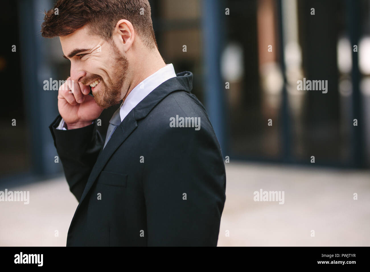 Smiling businessman talking over cell phone. Side view of