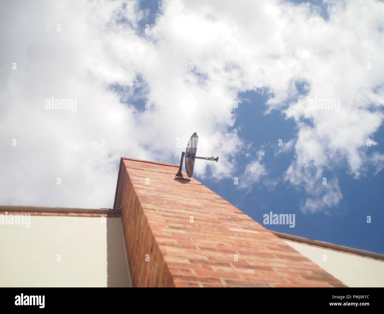 Satellite dish attached to chimney on modern house in the UK Stock