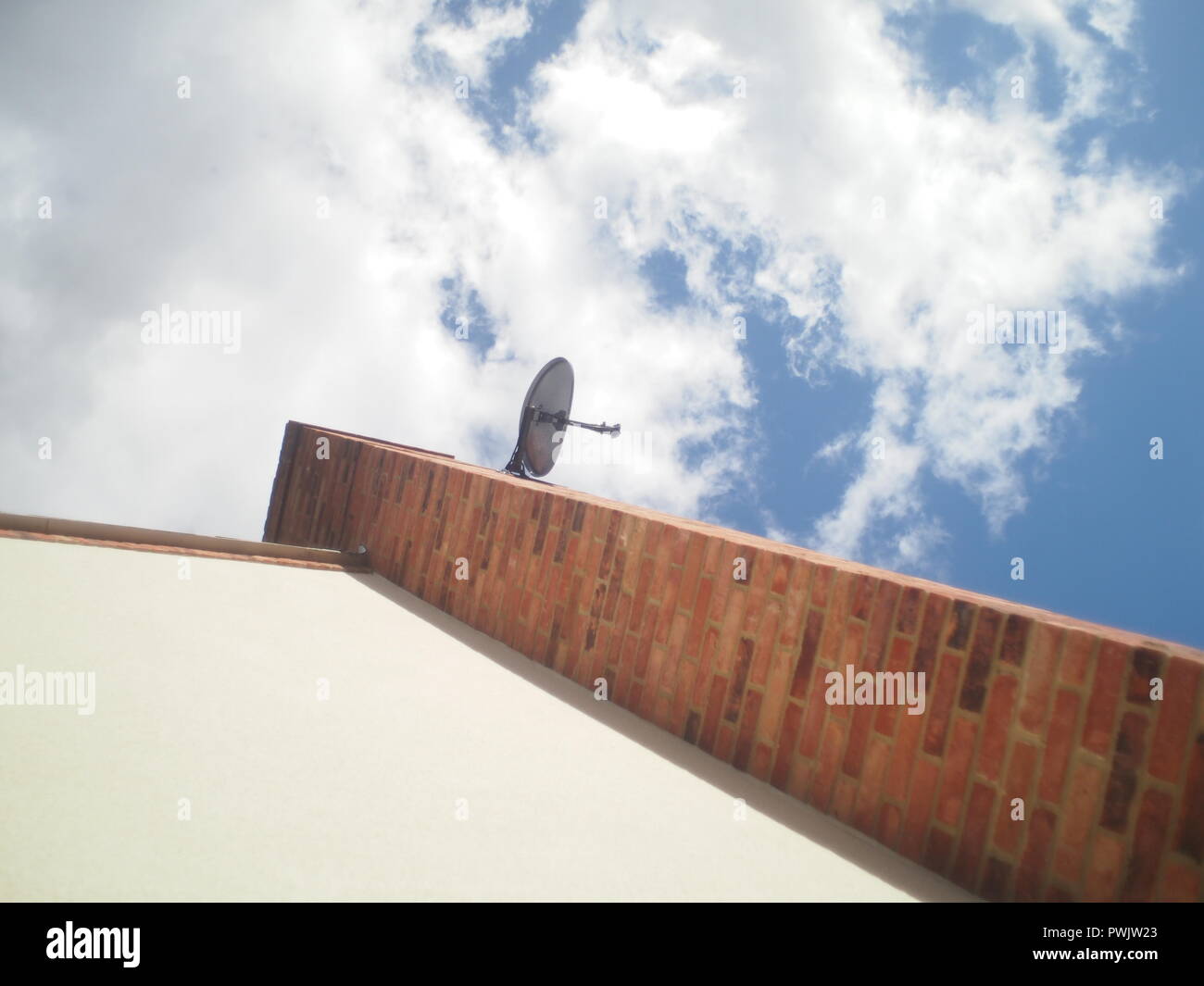Satellite dish attached to chimney on modern house in the UK Stock