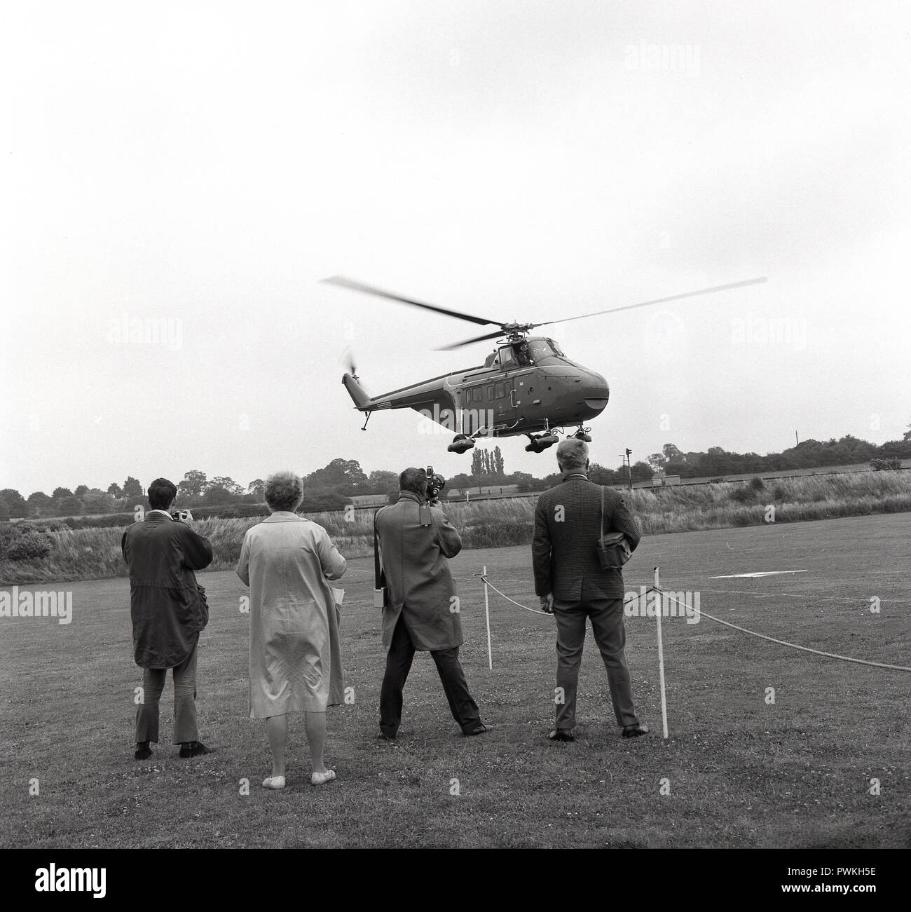 1960, members of the press await the arrival of the Royal helicopter coming into land in the grounds of Stoke Mandeville hospital, Aylesbury, Bucks, UK, for a Royal visit by Princess Marina, the Duchess of Kent. Stock Photo