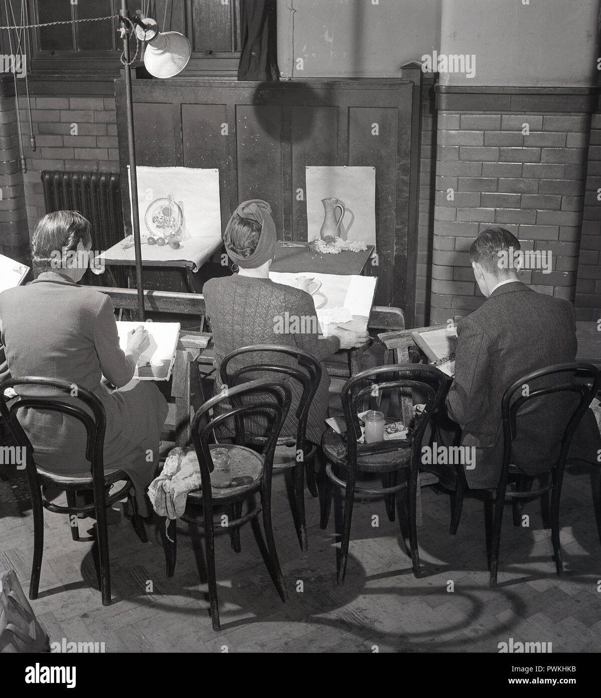 1950s, Britain,adults at an evening class, seating in a village  or churcj hall doing still life painting with water colours, England, UK. In post-war Britain there was no television, people made their own entertainment and so amtaeur dramatics, orchestras and evening classes were popular pasttimes. Stock Photo