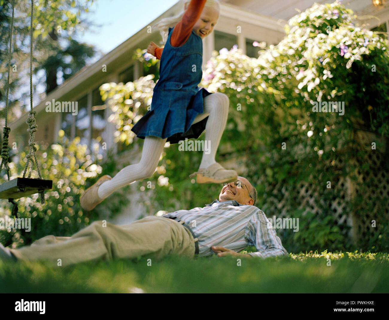 Mature man playing with his daughter in backyard. Stock Photo