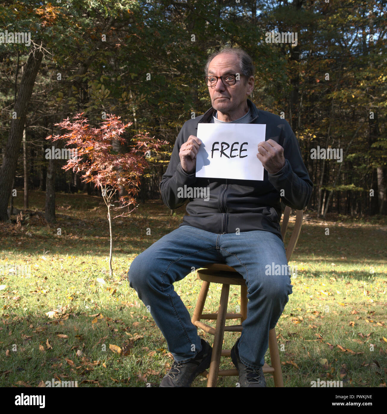 forlorn man on lawn holding free sign Stock Photo