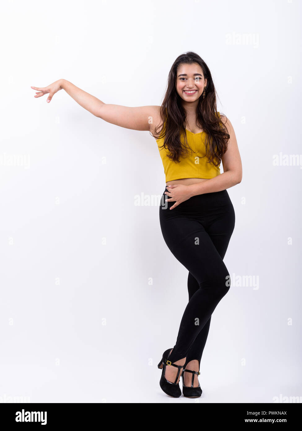 Full body shot of young happy Indian woman smiling while posing  Stock Photo