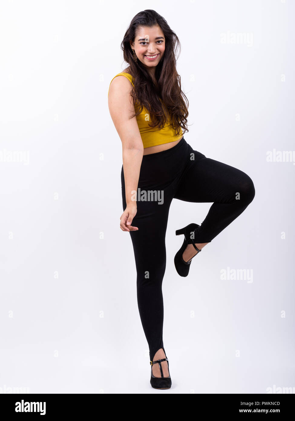 Full body shot of young happy Indian woman smiling while posing  Stock Photo