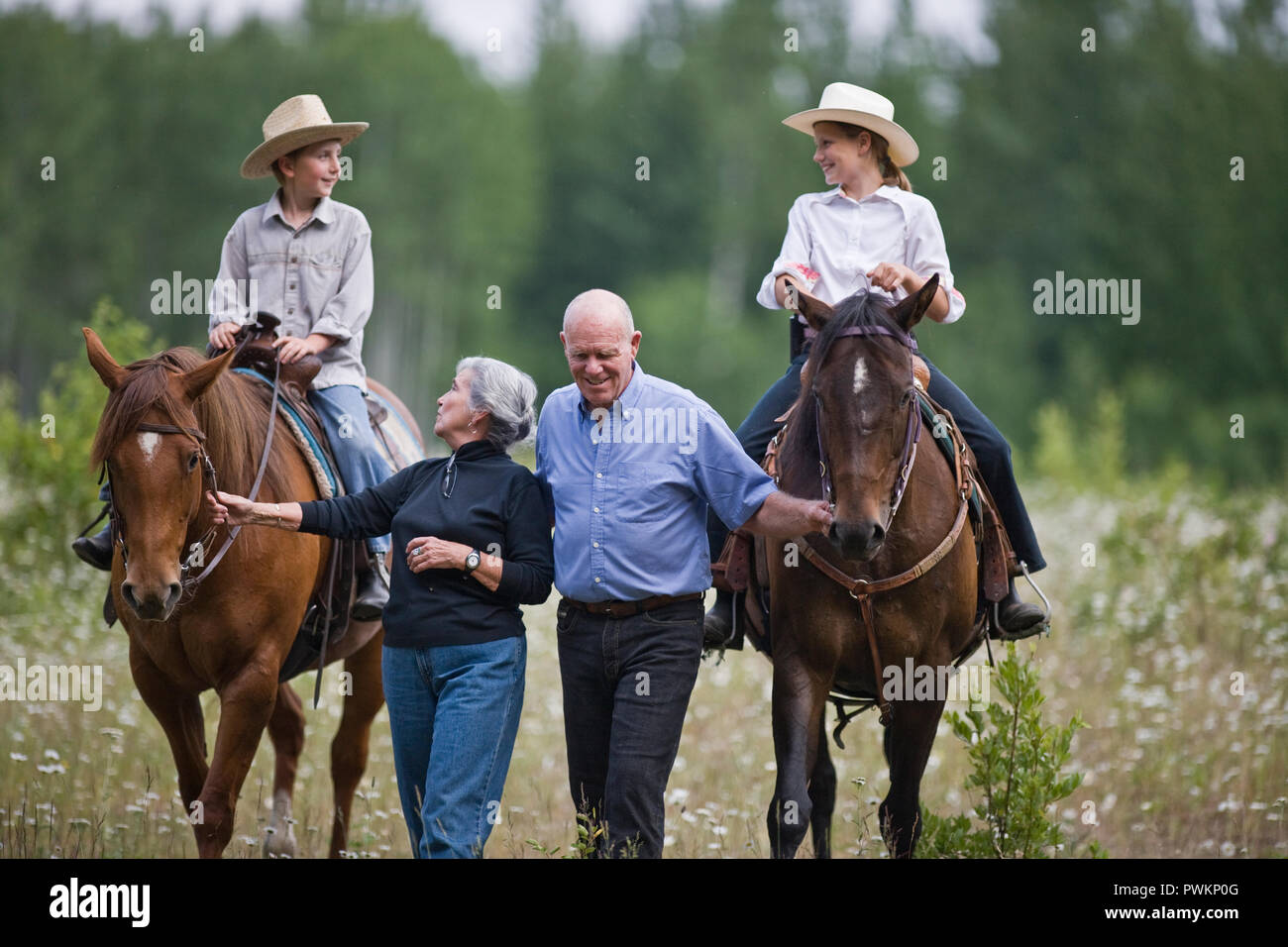 Grandparents leading horses ridden by grandchildren Stock Photo