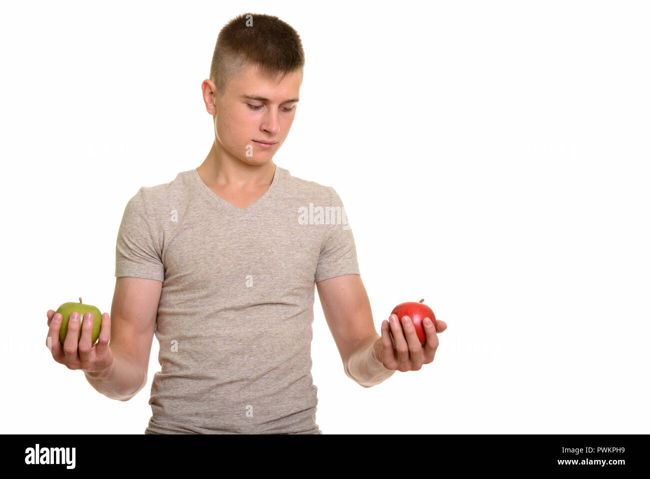 Young Caucasian man choosing between red and green apple Stock Photo