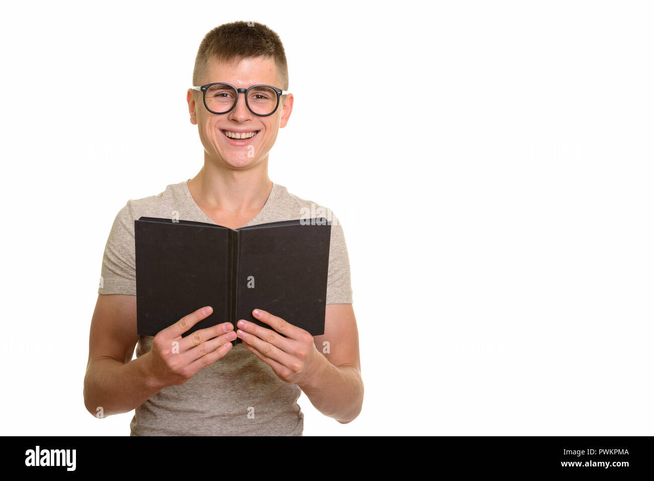 Young happy Caucasian man smiling and holding book Stock Photo