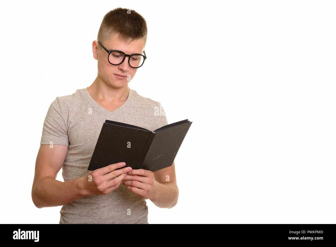 Young Caucasian nerd student man reading book Stock Photo