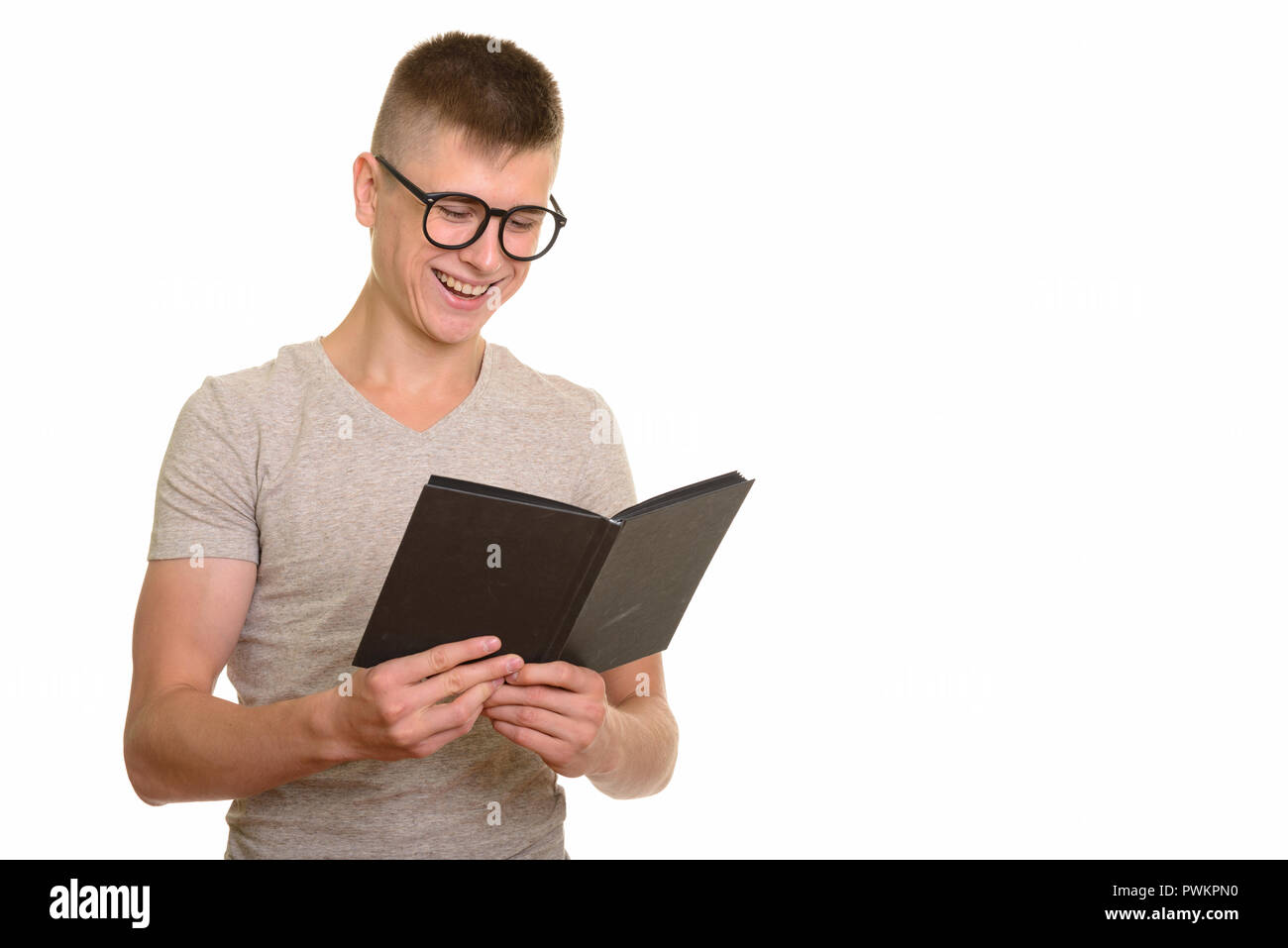 Young happy Caucasian man smiling and reading book Stock Photo