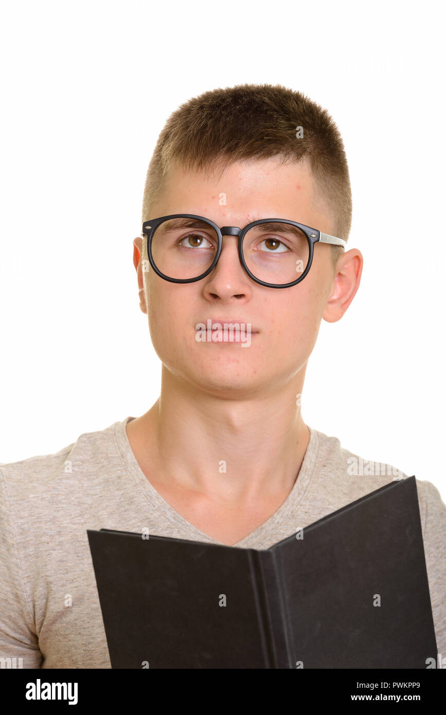Young Caucasian man holding book while thinking Stock Photo