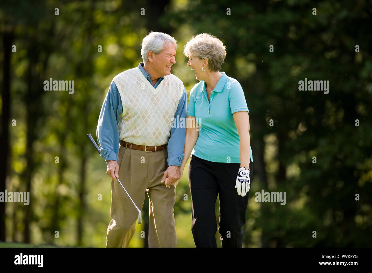 Older couple laughing on golf course Stock Photo