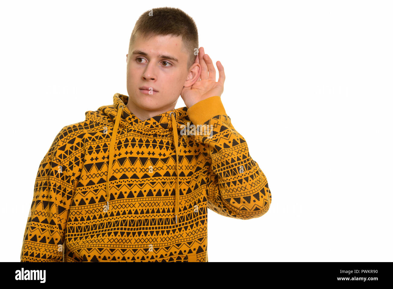 Young curious Caucasian man listening while cupping ear Stock Photo