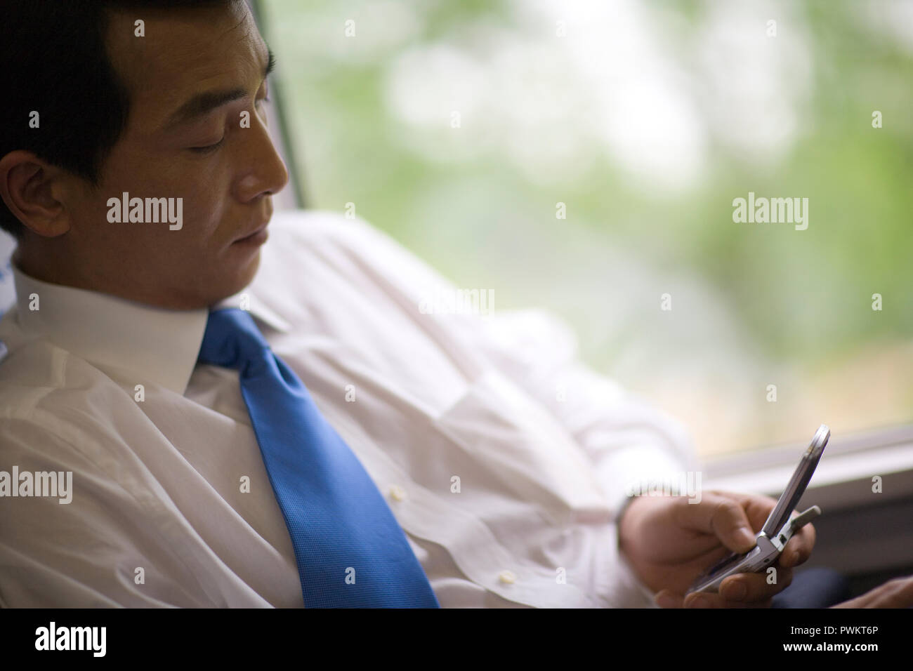 Mid-adult businessman sitting and texting on a train Stock Photo - Alamy