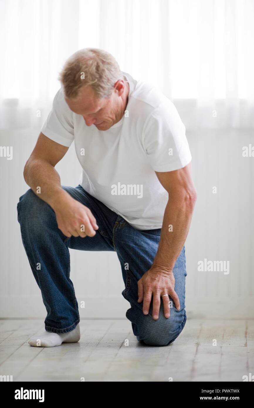Man kneeling on floor and looking down Stock Photo Alamy