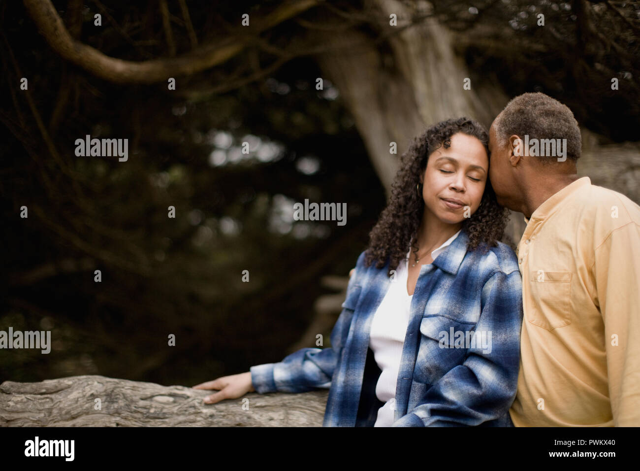 Mature couple leaning against a tree Stock Photo