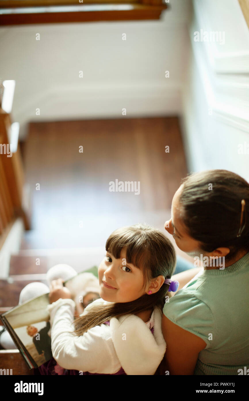 Woman and her young daughter sit on a flight of stairs. Stock Photo
