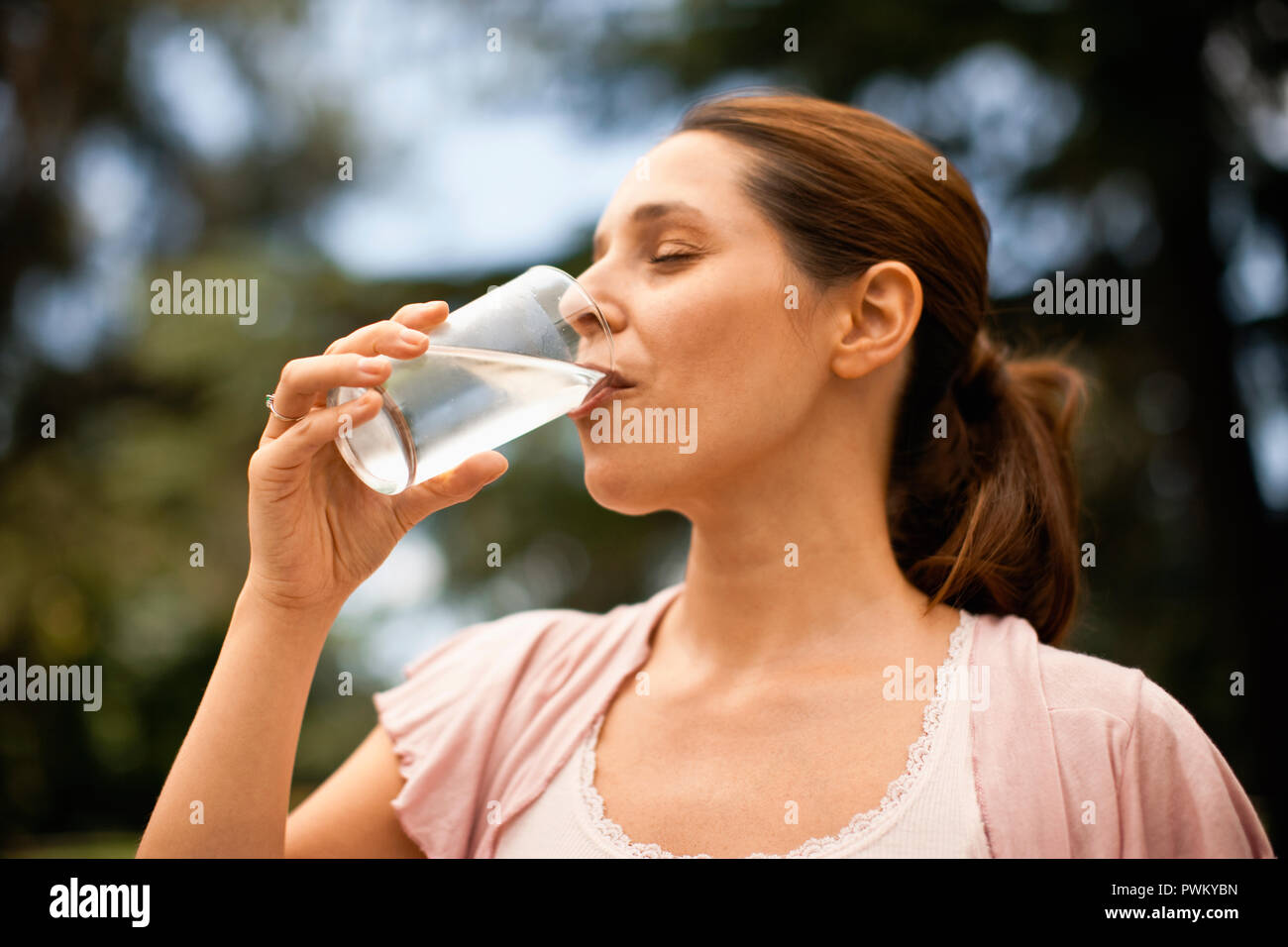 Twenty something woman drinks a glass of water. Stock Photo