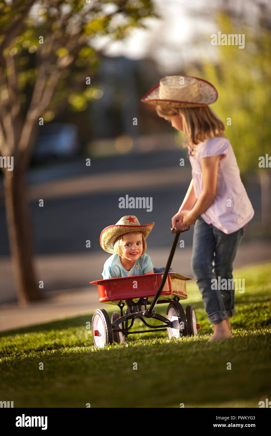 Girl pulling her younger sister in a red wagon Stock Photo Alamy