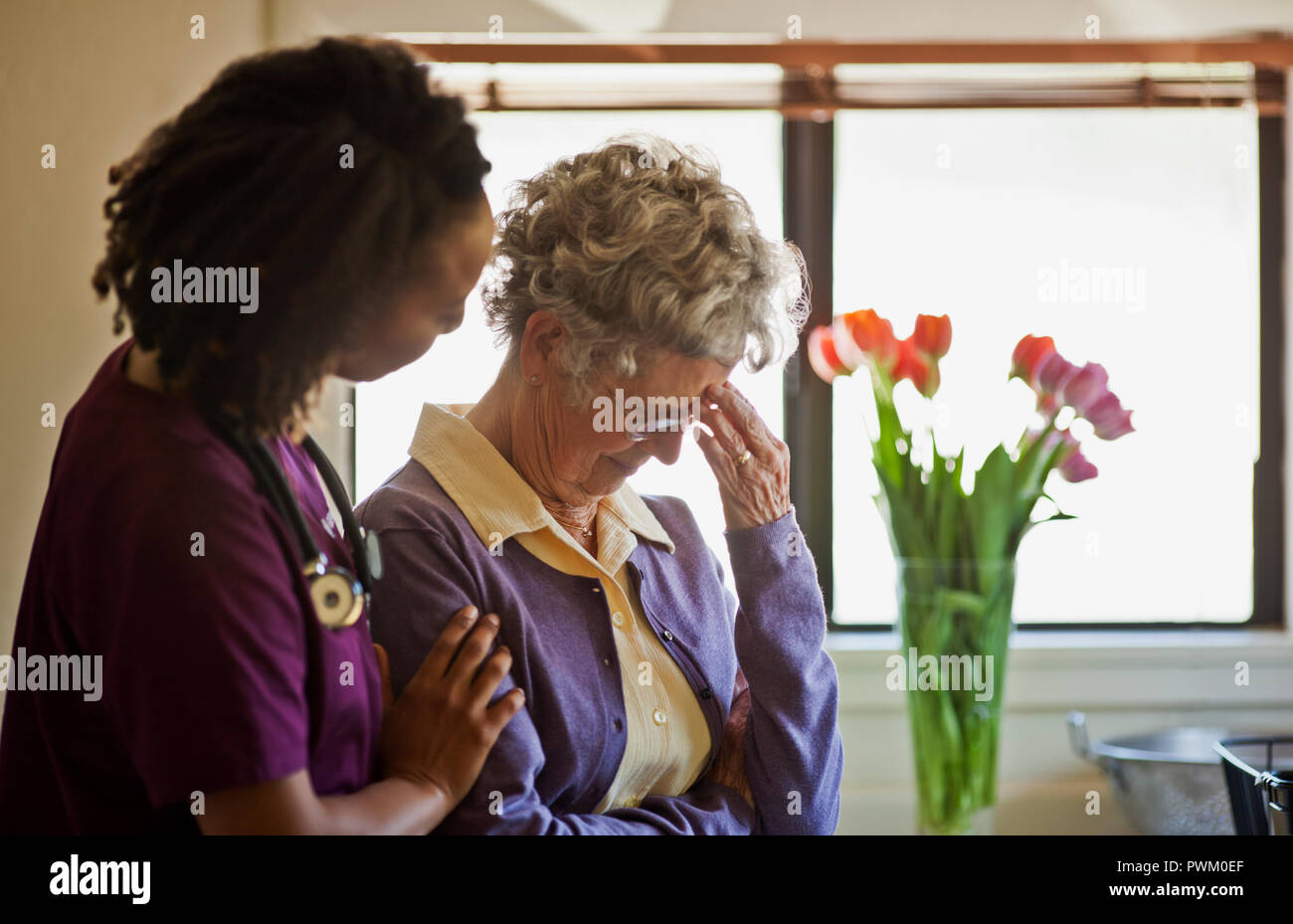 Young nurse comforting a grieving senior woman. Stock Photo