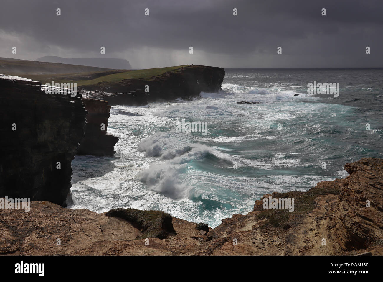 Dramatic waves along the cliffs at Yesnaby, Orkney Mainland, Scotland, UK as a storm blows in from the North Atlantic, rain and Hoy in the distance. Stock Photo