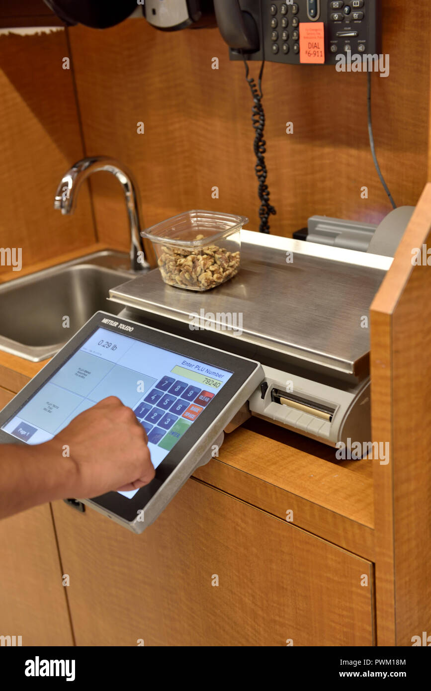 Customer weighing tray of self service walnuts to print price label in supermarket, USA Stock Photo