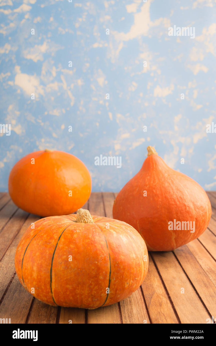 Three pumpkins on blue background on wooden table with copy space ...