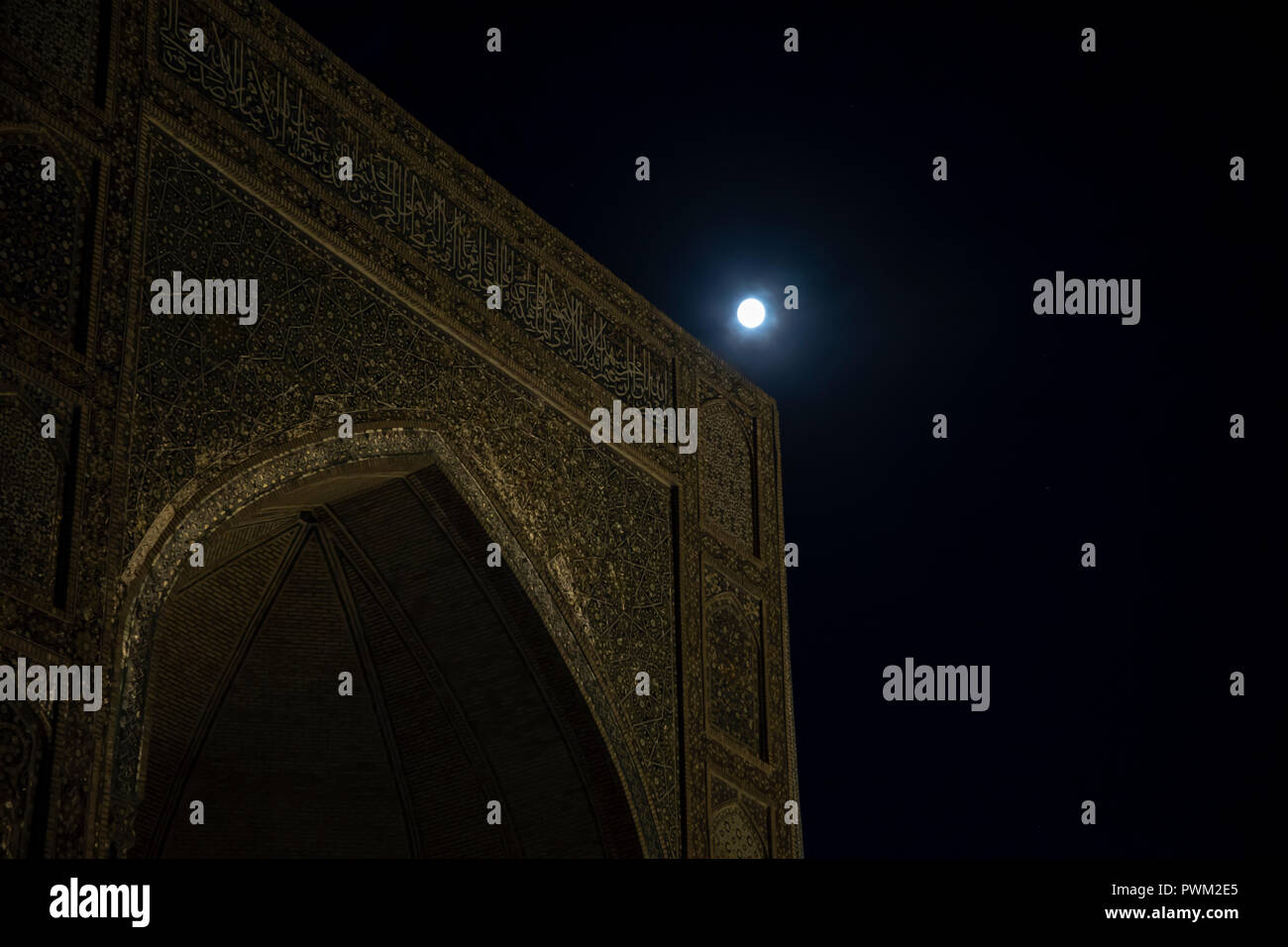 Full moon over entrance to Mir-i-Arab Madrasa illuminated at night in Bukhara, Uzbekistan. Stock Photo