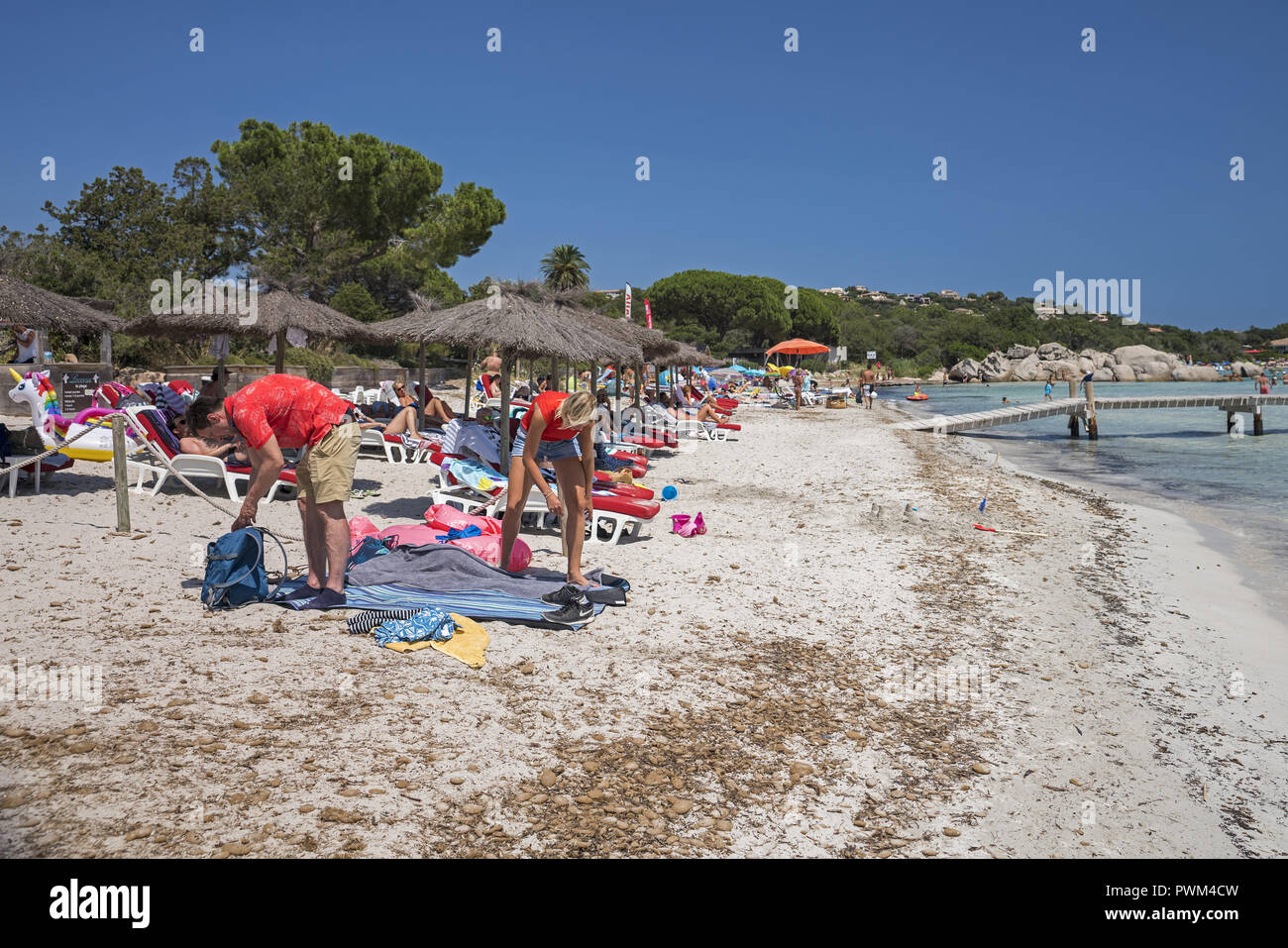 A couple unfolding a blanket on the beach. Beach of Santa Giulia in Corsica. Plaża Santa Giulia na Korsyce. Para rozkłada koc na plaży. Stock Photo