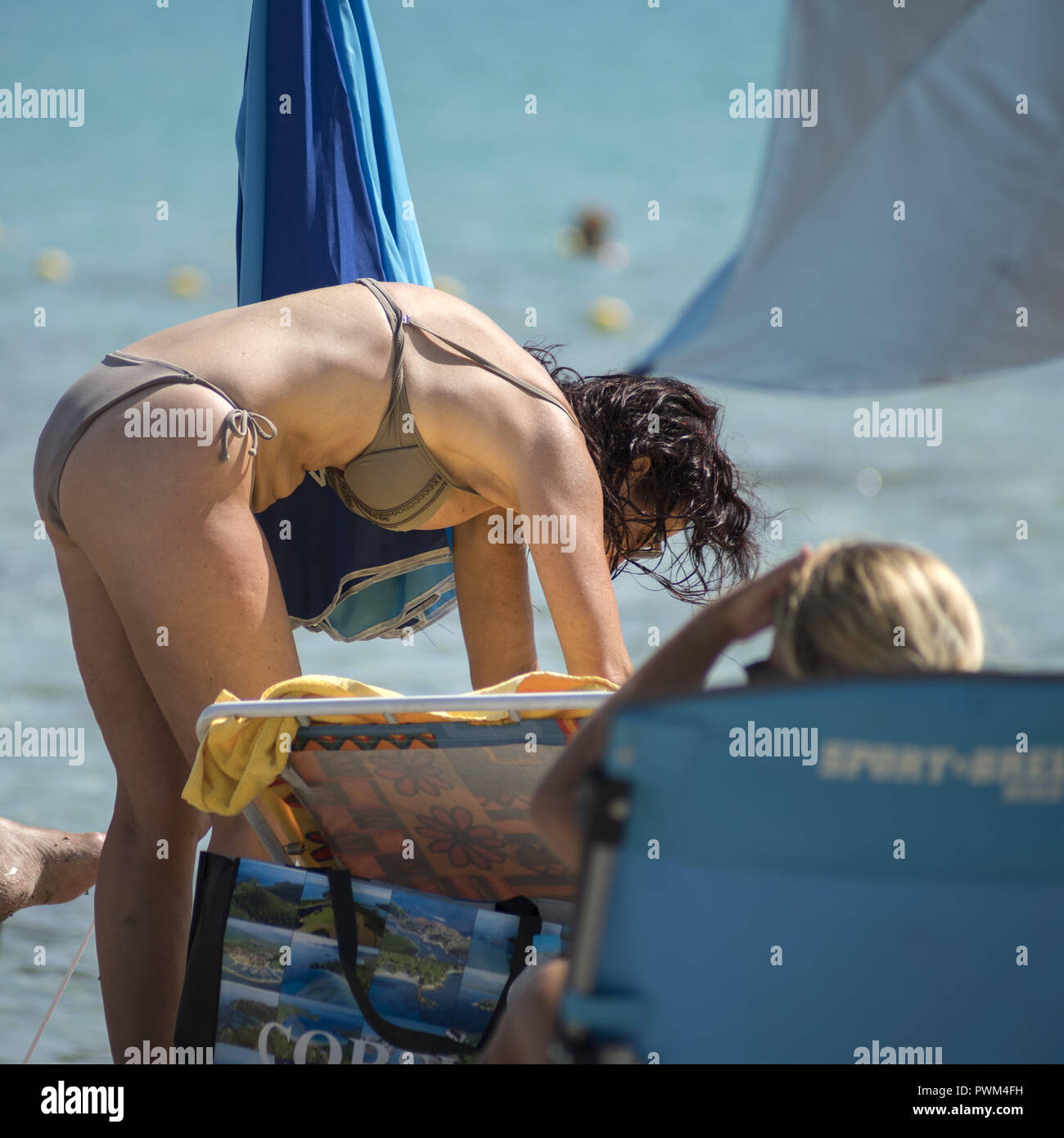 A bent butt-sticking mature woman with wet hair after bathing in the sea is  looking for something on the ground. Beach of Santa Giulia in Corsica Stock  Photo - Alamy