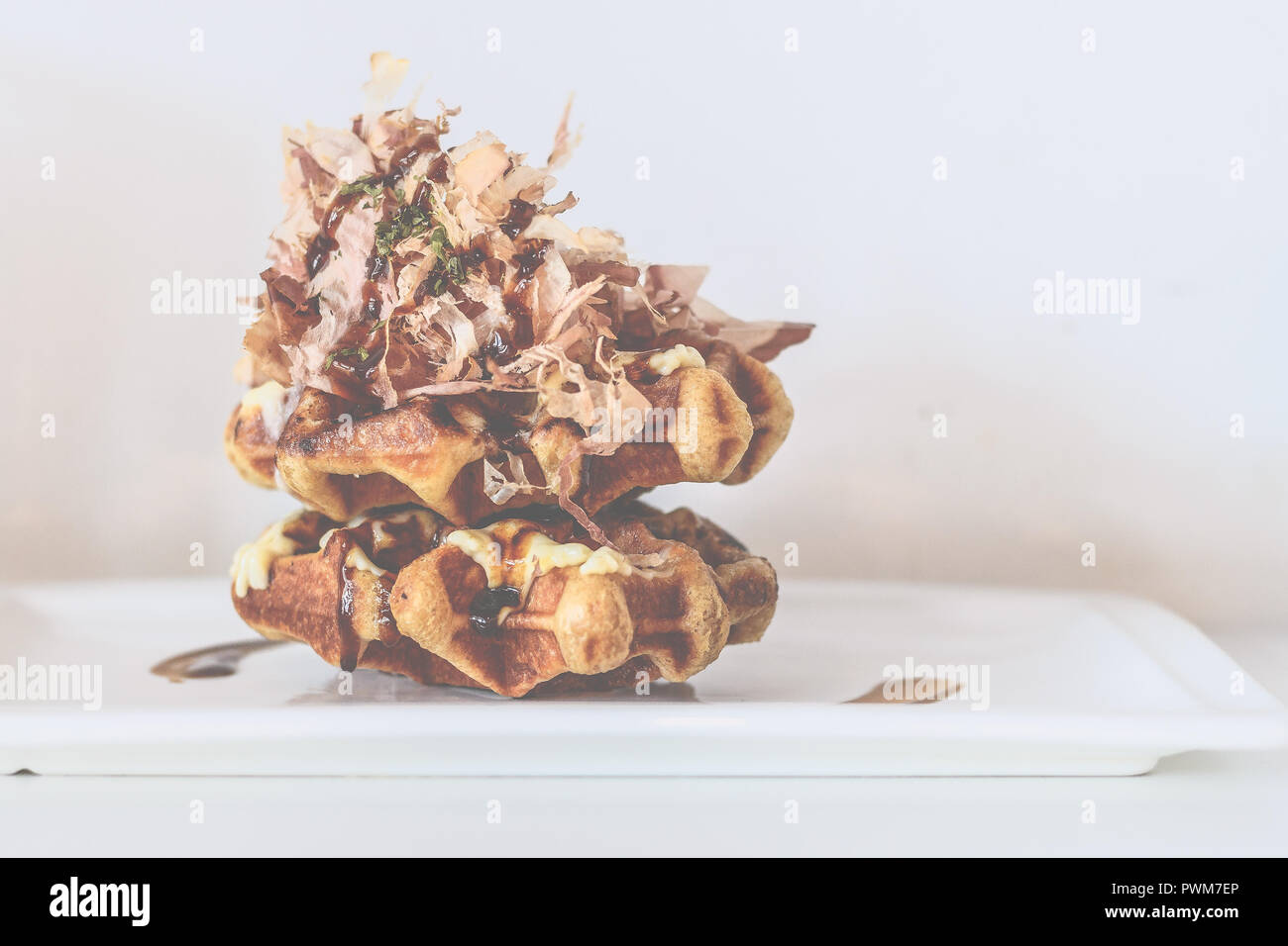Belgian Liege waffles topped with flamed takoyaki sauce, Japanese mayonnaise, Japanese spices and bonito flakes Stock Photo