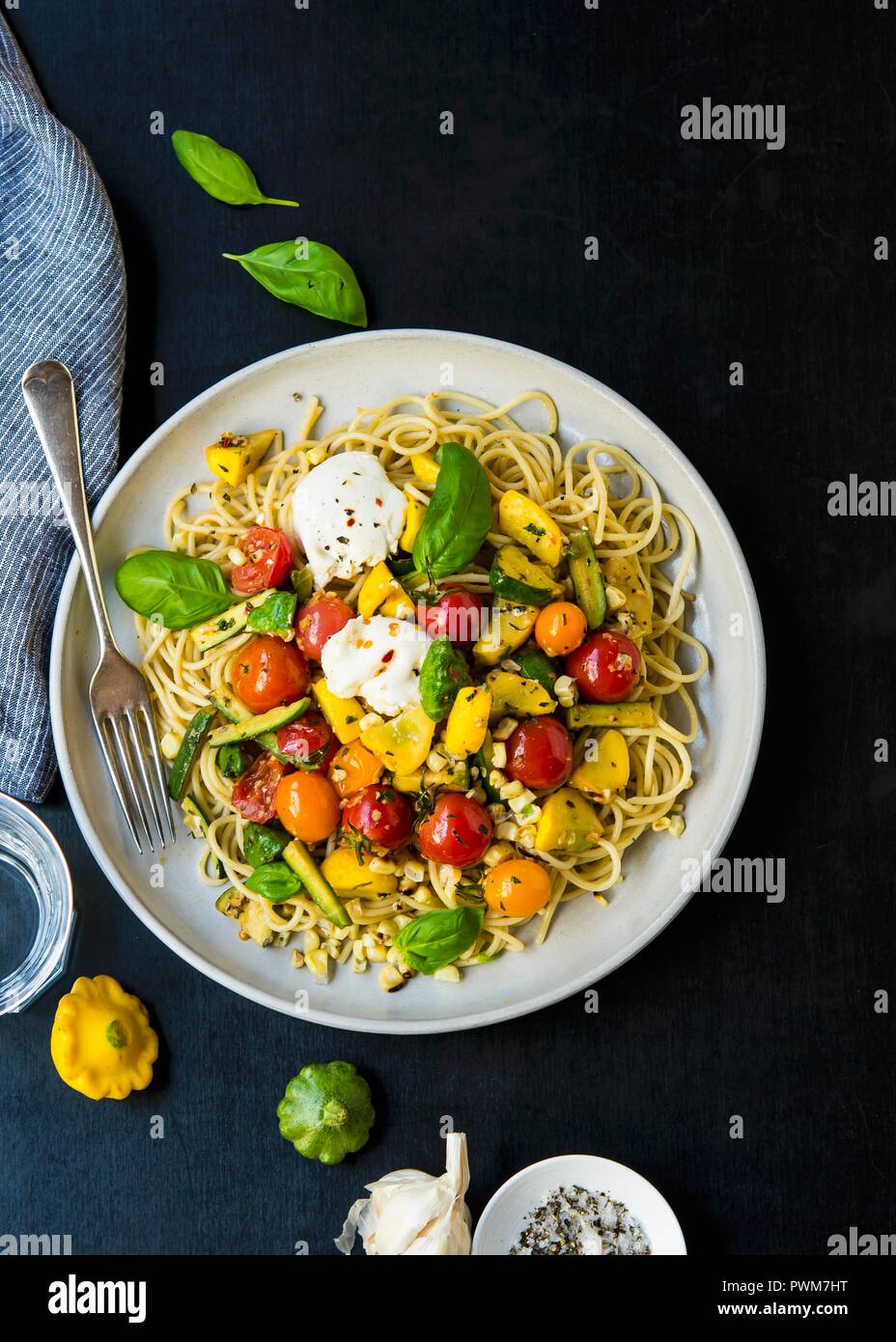 Spaghetti with anchovy paste, sautéed vegetables, burrata and basil Stock Photo