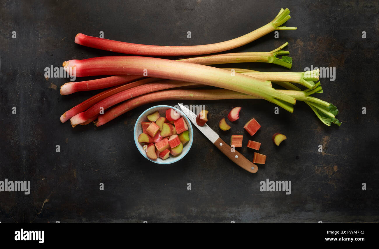 Rhubarb stems and chopped rhubarb in a bowl with a knife Stock Photo