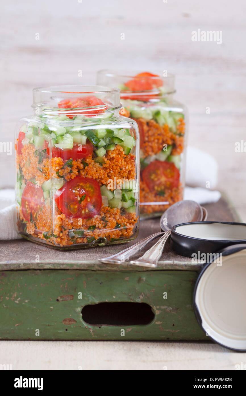 Bulgur wheat salad with pomegranate syrup, onions, cucumber, tomatoes, parsley and mint in a glass jar Stock Photo