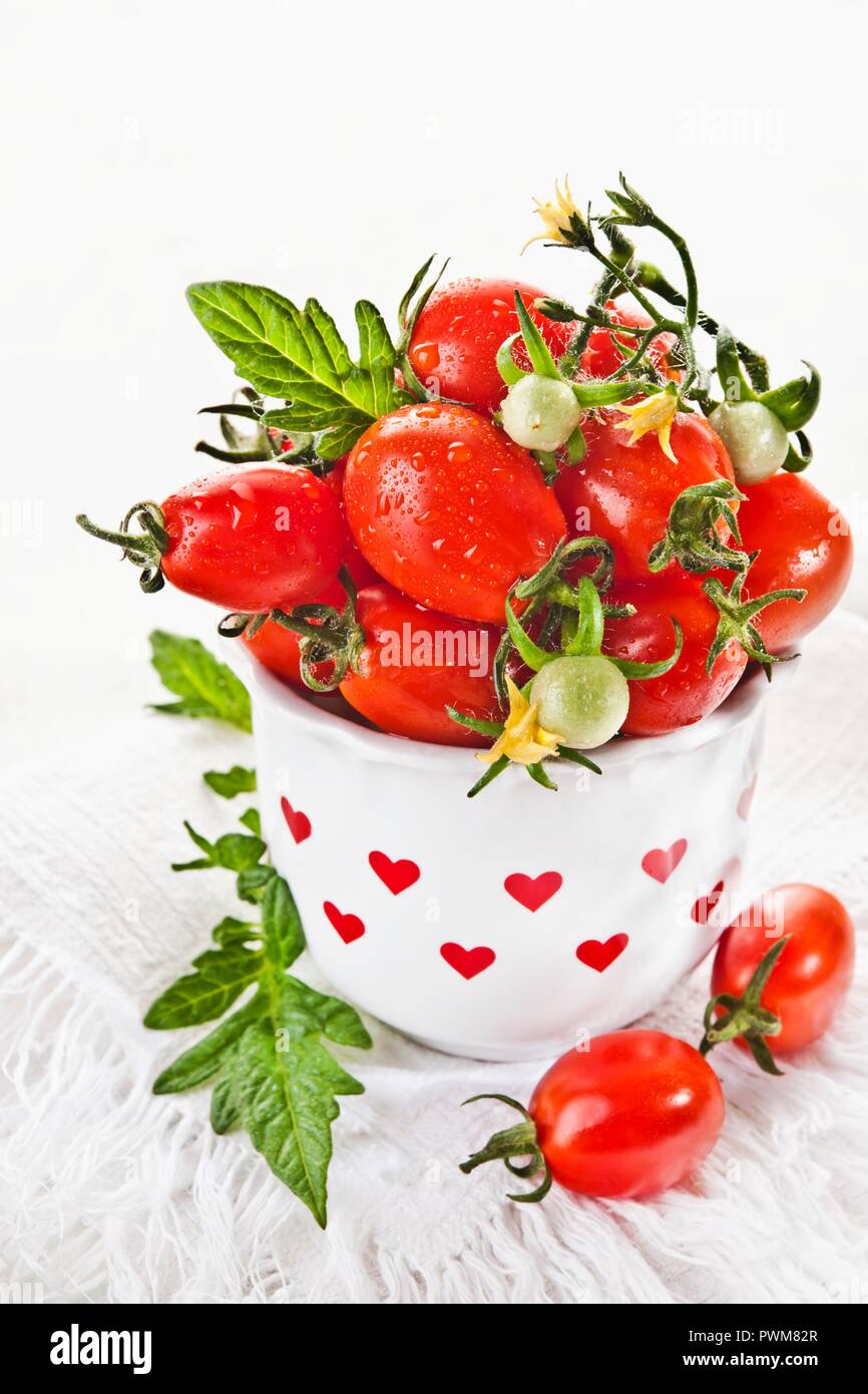 Cherry tomatoes in a vase decorated with red hearts Stock Photo