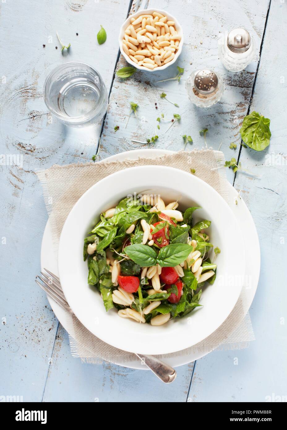 A bowl of pasta and spinach salad with tomatoes and pine nuts Stock