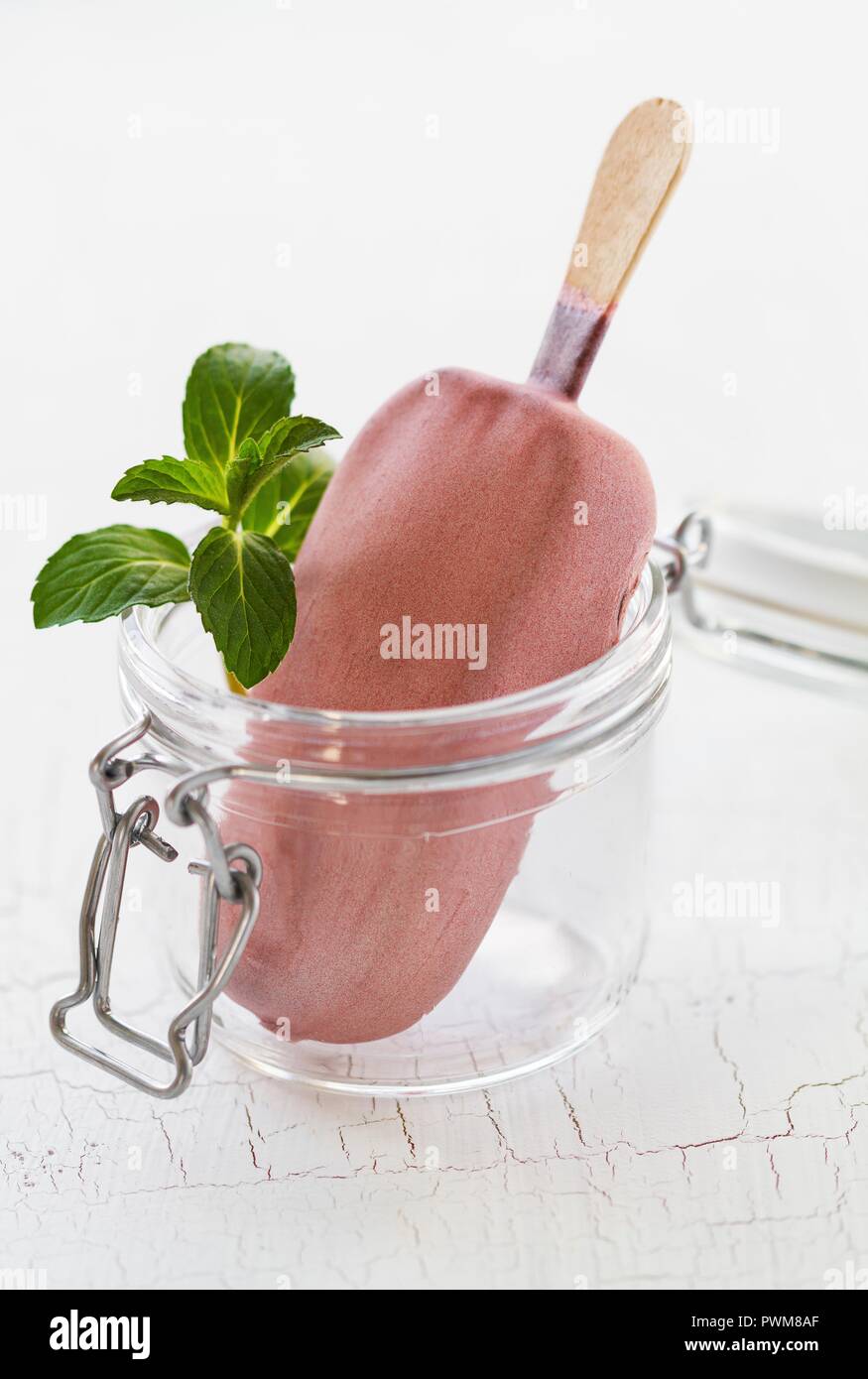 Raspberry ice cream on a stick with mint in a glass jar Stock Photo