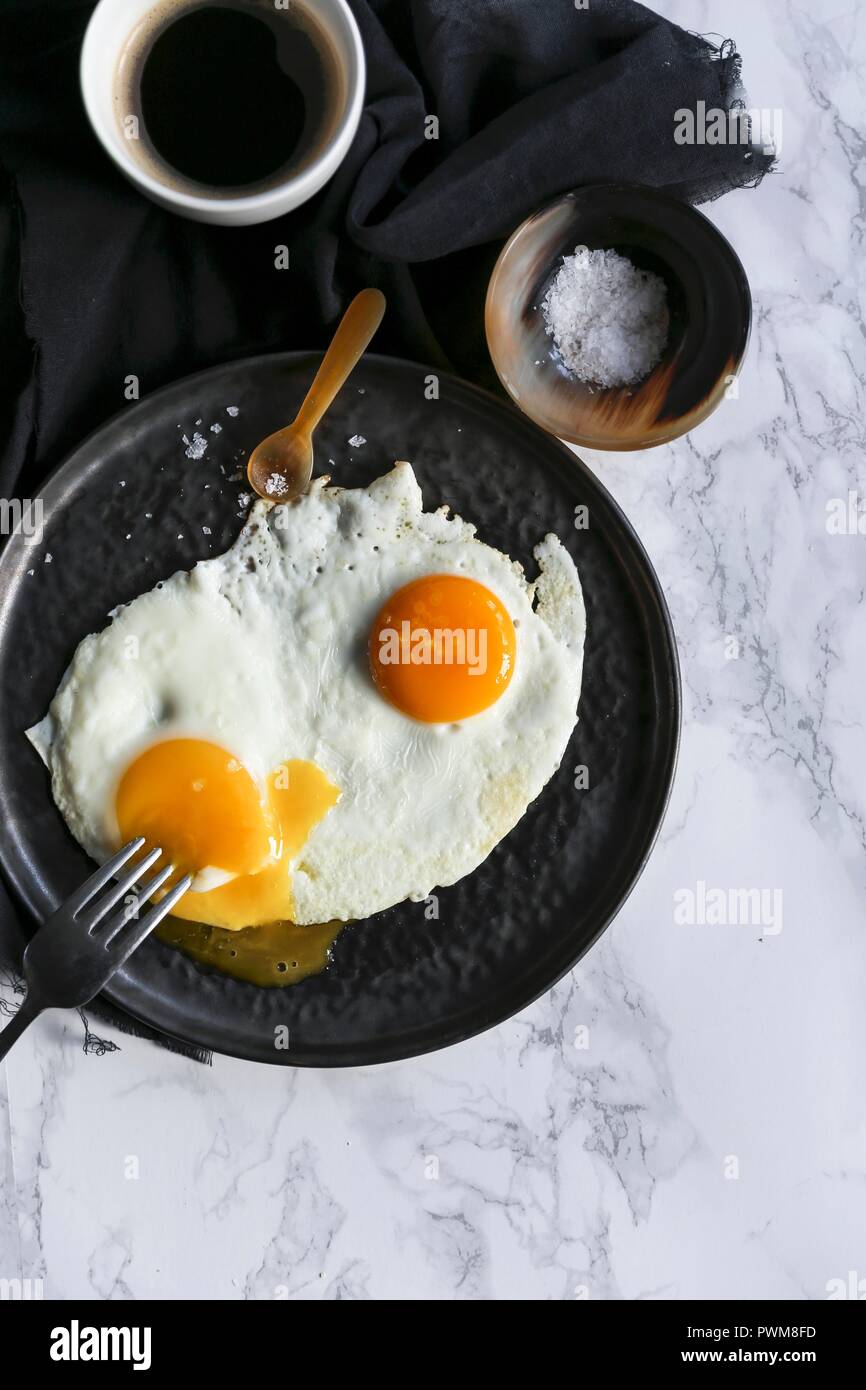 A fried egg with salt and a cup of coffee Stock Photo