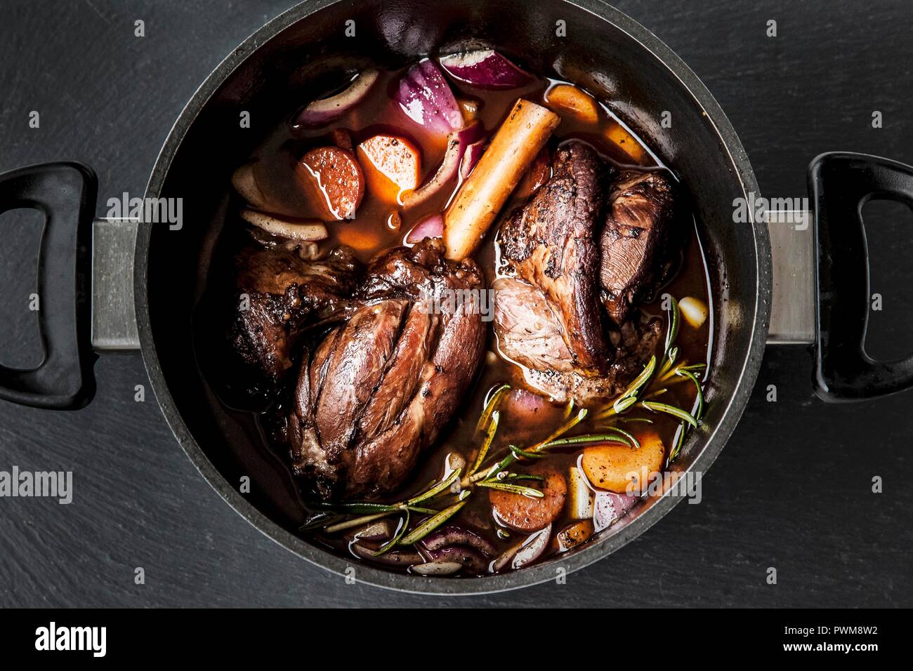 Leg of lamb in red wine with onions, carrots and rosemary Stock Photo