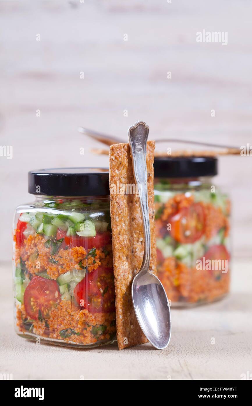 Bulgur wheat salad with pomegranate syrup, onions, cucumber, tomatoes, parsley and mint in a glass jar Stock Photo