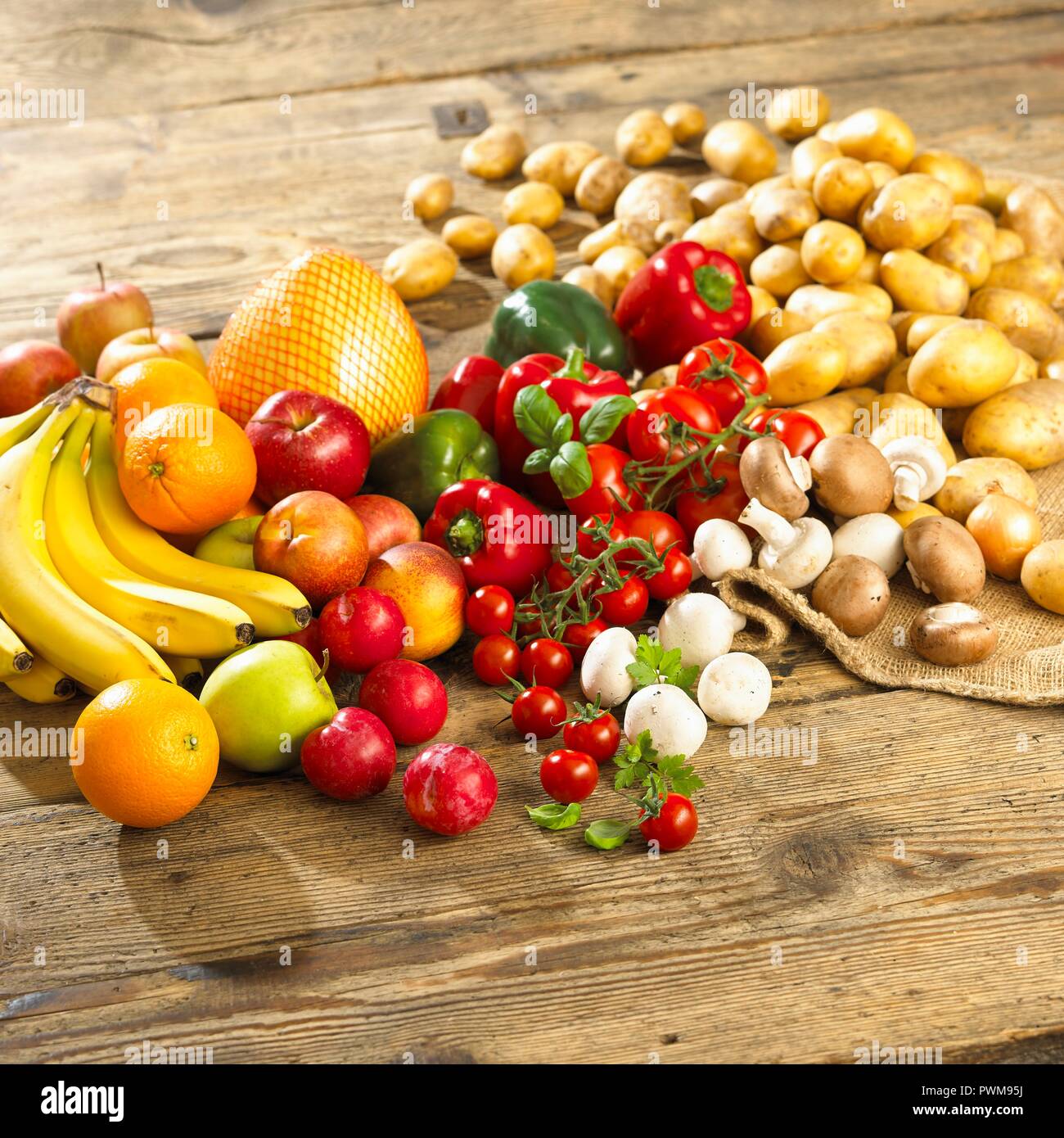 An arrangement of vegetables, mushrooms and fruit on a wooden table Stock Photo