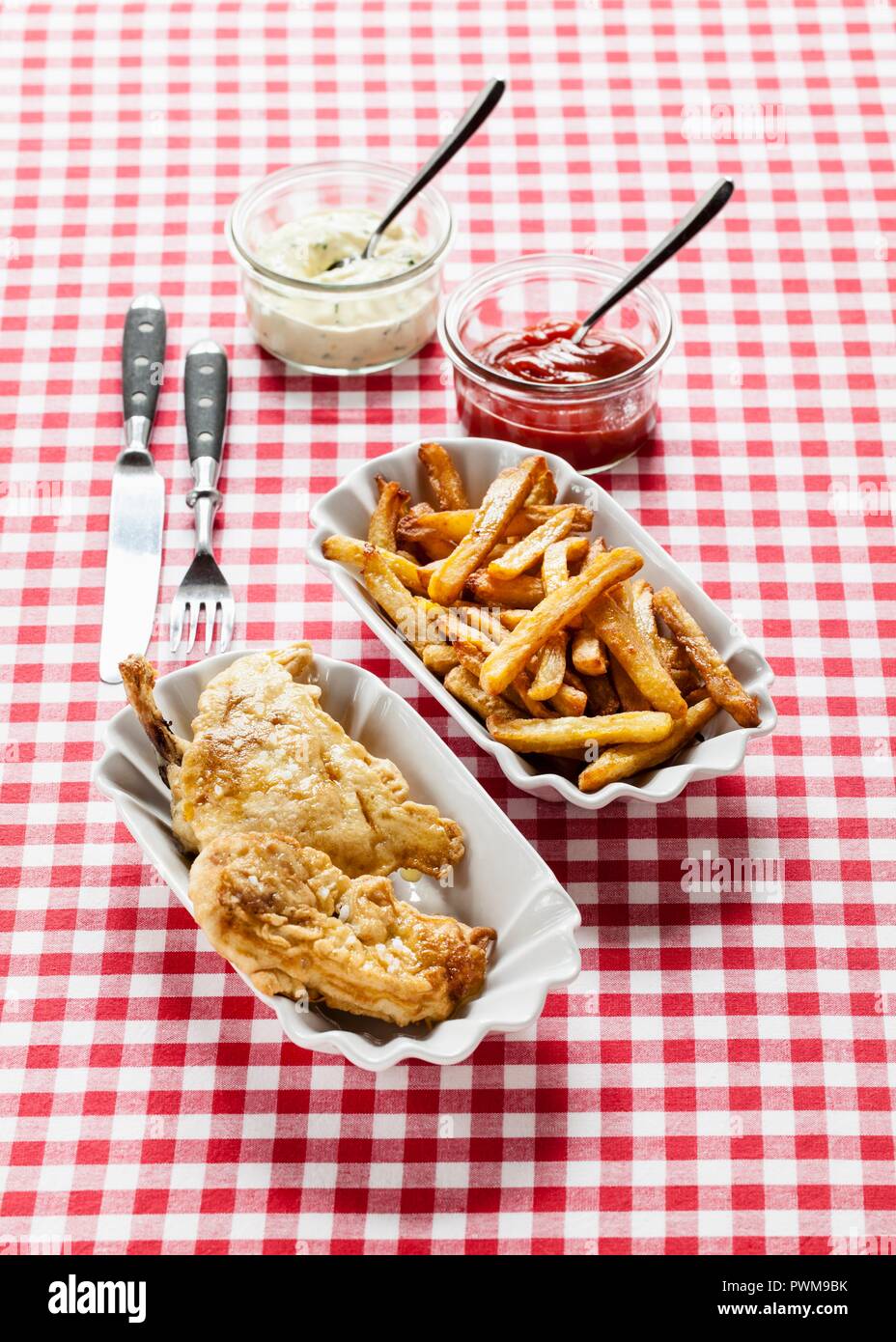 Fried chicken with chips, ketchup and remoulade on a checked tablecloth