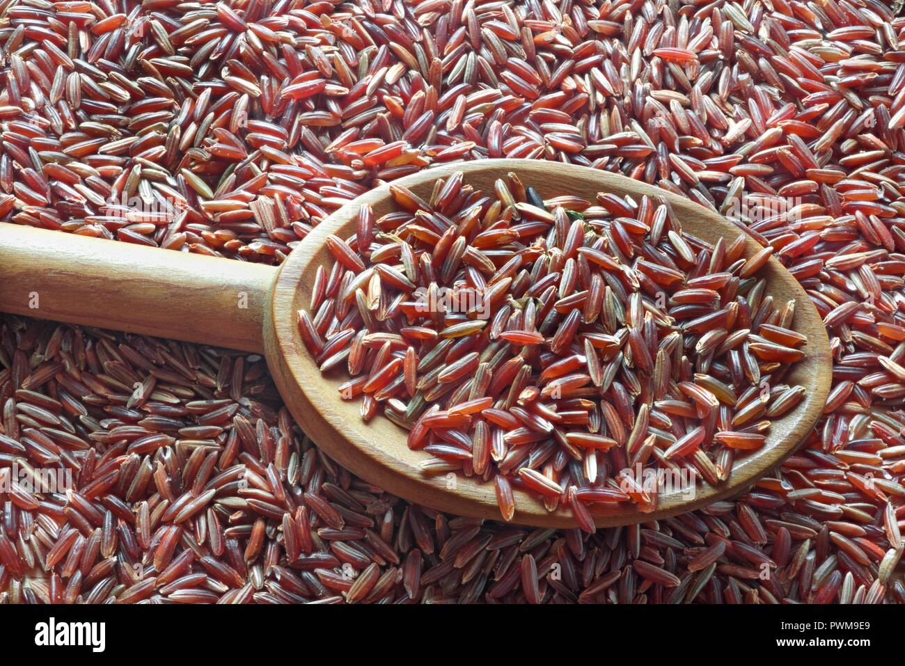 Red rice on a spoon on top of a pile of red rice Stock Photo - Alamy